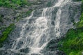 Atmospheric view of waterfall on river. Swift stream among rocks and green moss