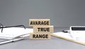 ATR Average True Range text on wooden block with notebook,chart and calculator, grey background Royalty Free Stock Photo