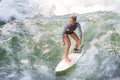 Atractive sporty girl surfing on famous artificial river wave in Englischer garten, Munich, Germany.