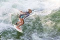 Atractive sporty girl surfing on famous artificial river wave in Englischer garten, Munich, Germany.