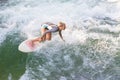 Atractive sporty girl surfing on famous artificial river wave in Englischer garten, Munich, Germany.