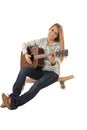 Atractive woman sitting on skate board playing guitar Royalty Free Stock Photo