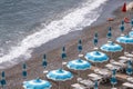 Rows of blue and white parasols and sunbeds on the beach at Atrani on the Amalfi Coast, Italy.