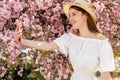 Atrractive Young Girl Having Video Chat on Modern Smartphone While Standing Outdoors. Stylish Brunette in Straw Hat