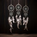 3 attache dWhite dream catcher with feather hanging at black wooden background