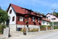 Attached newly built wooden and concrete small suburban family house with metal fence and flowers in front