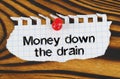 Attached to the board is an announcement with the inscription - Money down the drain Royalty Free Stock Photo