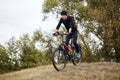 Attaractive man wearing blacktrack suit and cap riding dowhill on his mountain bike, having cardio training, enjoying his Royalty Free Stock Photo