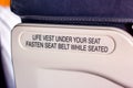 Attention announcement for passengers about emergency life vest and the seatbelt on the seat back inside the airplane cabin. Royalty Free Stock Photo