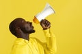 Attention! Black man shouting in megaphone on yellow background Royalty Free Stock Photo