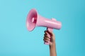 Attention grabber Hand with blue megaphone against pink backdrop, free