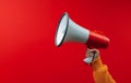 Attention grabbing image Hand holds megaphone against red background Royalty Free Stock Photo