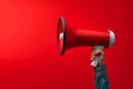Attention grabbing image Hand holds megaphone against red background Royalty Free Stock Photo