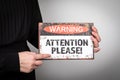 Attention please. Warning sign in a woman's hands on a light background Royalty Free Stock Photo