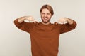 Attention to advertising below! Portrait of excited enthusiastic handsome bearded man pointing down and smiling