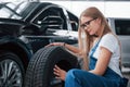 Attention to details. Sitting with new wheel near the new luxury perfectly polished car. Ready to replacement Royalty Free Stock Photo