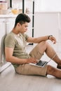 Asian man using laptop while sitting on floor in kitchen Royalty Free Stock Photo