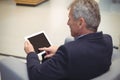 Attentive businessman sitting on sofa and using digital tablet