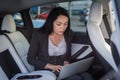 Attentive businesswoman working with laptop, looking at screen, typing while sitting on the back seat of car. Business Royalty Free Stock Photo