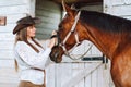 Attentive horsewoman equestrienne in hat. Cleaning muzzling grooming horse mane. Animal care harness. Horse back riding.