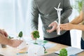 Attentive creative engineers holding miniature windmill turbines and houses