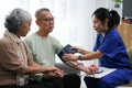 Attentive doctor or healthcare worker giving professional advice to senior couple during home visit