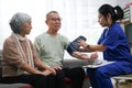 Attentive doctor or healthcare worker giving professional advice to senior couple during home visit