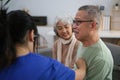 Attentive doctor or healthcare worker giving professional advice to senior couple during home visit