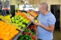Elderly man purchaser buying fresh apples in grocery store