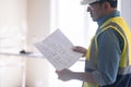 Attentive engineer standing in light unfinished premise studying project drawing