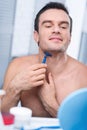 Attentive focused man shaving his neck
