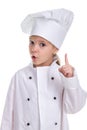 Attentive girl chef white uniform isolated on white background, looking straight at the camera with a pointing finger up