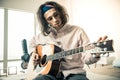 Attentive good-looking man with wavy hair tuning strings on acoustic guitar