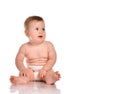 Attentive infant child baby boy in a diaper sitting on a white background.