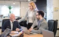 Businesswoman and young businessman listening to senior boss talking during meeting around table in office Royalty Free Stock Photo