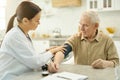 Attentive medic preparing to measure elderly man blood pressure