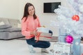 Attentive mother is preparing presents for children on winter holidays, putting them under the firtree.