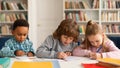 Attentive multiracial schoolkids boys and girl writing test, sitting at desk in classroom at primary school, panorama Royalty Free Stock Photo