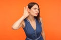 Attentive nosy brunette woman in denim dress overhearing, listening intently to secret Royalty Free Stock Photo