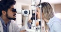 Attentive optometrist examining female patient on slit lamp