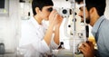 Attentive optometrist examining female patient on slit lamp