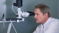 Attentive optometrist examining male patient on slit lamp in ophthalmology clinic