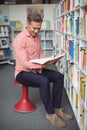 Attentive school teacher holding book in library