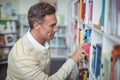 Attentive school teacher selecting book in library