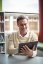 Attentive school teacher using digital tablet in library