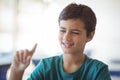 Attentive schoolboy gesturing in classroom