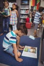 Attentive schoolboy reading book in library