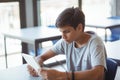 Attentive schoolboy using digital tablet in classroom