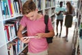 Attentive schoolboy using digital tablet in library Royalty Free Stock Photo