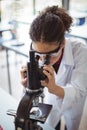 Attentive schoolgirl looking through microscope in laboratory